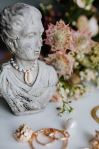 Kaboompics - Gold jewellery in white marble - flowers and a small sculpture, a shell
