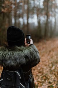 A woman takes a picture with her iPhone X in the autumn forest