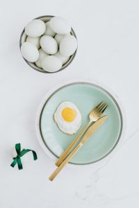 Easter flat lay with green eggs and fried egg on a plate