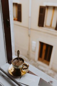 Kaboompics - Drink coffee in a golden cup at the window