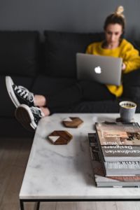 Kaboompics - Woman with legs on the coffee table, wearing converse sneakers and working on her laptop