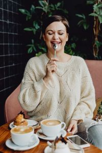 A woman drinks coffee and eats a dessert in a café