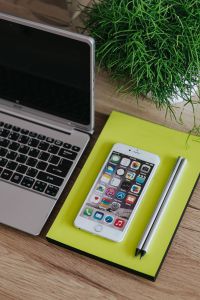 Kaboompics - Silver Acer laptop, a white Apple iPhone, a yellow notebook and a green plant on a wooden desk