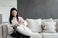 Young Asian woman improves cushions on linen couch