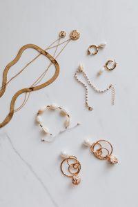 Gold jewellery on white marble - necklace, bracelets, earrings