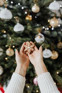 Kaboompics - Woman holds a gingerbread cookie, Christmas tree background