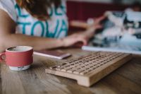 Kaboompics - Woman with wireless wooden keyboard and cup of coffee