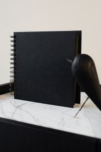 Kaboompics - blackbook & wooden bird on marble