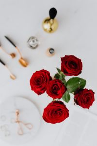 Kaboompics - Red roses, gold rings, perfume brushes and make-up accessories on white marble
