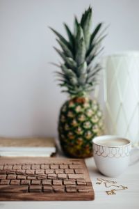 Kaboompics - Wooden keyboard, cup of coffee, pineapple and golden jewellery