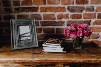Kaboompics - Photo frame, books and pink flowers in a vase on a wooden commode