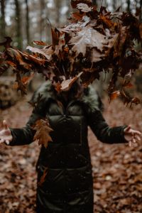 Kaboompics - A woman throws up the autumn brown leaves