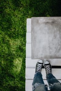 Kaboompics - Concrete side table and green grass in garden, woman, jeans, sneakers