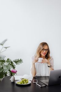 Kaboompics - A businesswoman drinks coffee in the office at her desk