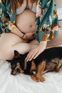 Pregnant woman petting a small black dog