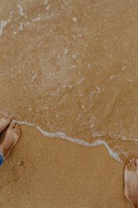 Closeup of sand, feet and small wave