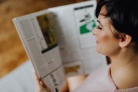 Kaboompics - A woman with short dark hair reads a newspaper