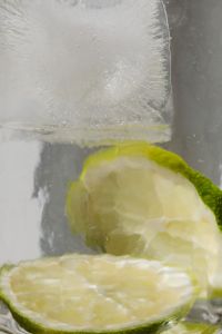 Tall glass with water - lime - ice cubes - close up - closeup