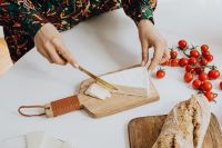 Kaboompics - Woman is cutting cheese on cutting board