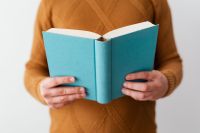 Kaboompics - A man in a brown sweater reading a book, white background