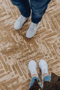 A couple in sports shoes standing on an old brick floor