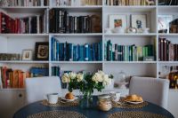 Round breakfast table with white flowers by the bookcase
