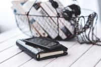 Black smartphone and headphones and a basket of books
