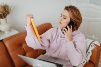 Kaboompics - Woman uses laptop - working from home - talking on the mobile phone about book