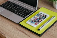 Kaboompics - Silver Acer laptop, a white Apple iPhone and a yellow notebook on a wooden desk