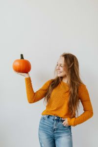 Kaboompics - A young girl holds a pumpkin in her hand