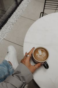 Cozy Indoor Scene - Woman Enjoying a Cup of Coffee at a White Marble Table