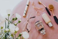 Kaboompics - Makeup brushes, eyelash curler & a bottle of perfume on pink velvet