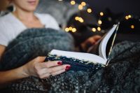 Kaboompics - Young woman at home reading Hygge book and drinking
