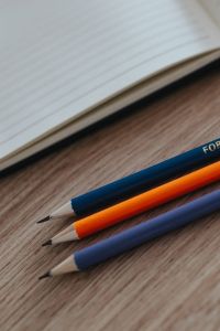 Kaboompics - Notebooks with colourful pencils on a wooden desk