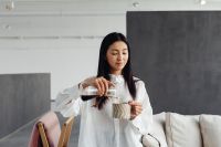 Kaboompics - An Asian adult woman pours coffee from a Chemex into a cup