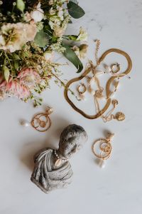 Kaboompics - Gold jewellery in white marble - flowers and a small sculpture, a shell