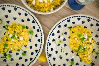 Kaboompics - Yellow rice with greens on a cute plate with blue hearts and a table decorated with flower petals