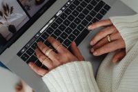Woman in white sweater - gold rings - jewelry - jeans - laptop - work
