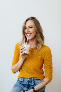 Kaboompics - A joyful young woman drinks a McDonald's milkshake