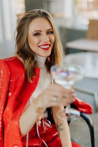 Woman in a red jacket holds a glass