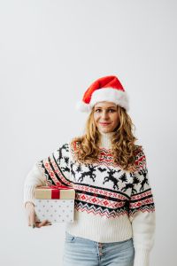 Woman with Gift Wearing Christmas Sweater and Santa Hat