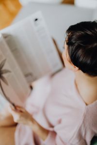 A woman with short dark hair reads a newspaper