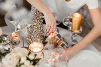A woman decorates a Christmas table with silver decorations and white porcelain tableware