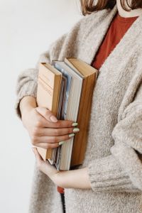 Kaboompics - A young woman in a woolly sweater holds books