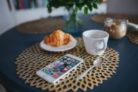 Kaboompics - Coffee cup with a croissant and a smartphone on a golden mat
