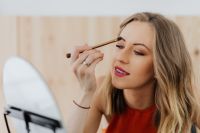 Kaboompics - Young woman sitting and doing makeup in front of mirror