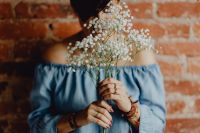 A woman in a blue dress holds a branch of Baby's Breath flower