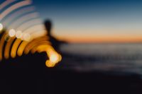 Kaboompics - Light painting. The man waving fairy lights at the sea at sunset.