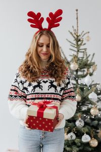 Woman with Gifts Wearing Christmas Sweater and Reindeer Horns on Head