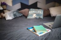 Kaboompics - Laptop with books on a bed